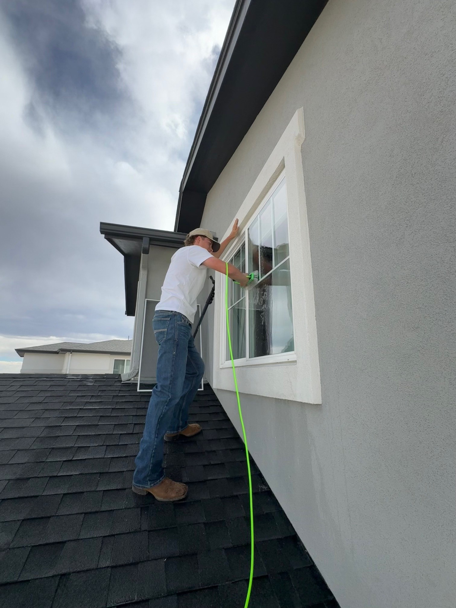 Red Wagon Windows team member cleaning an exterior window from the roofline