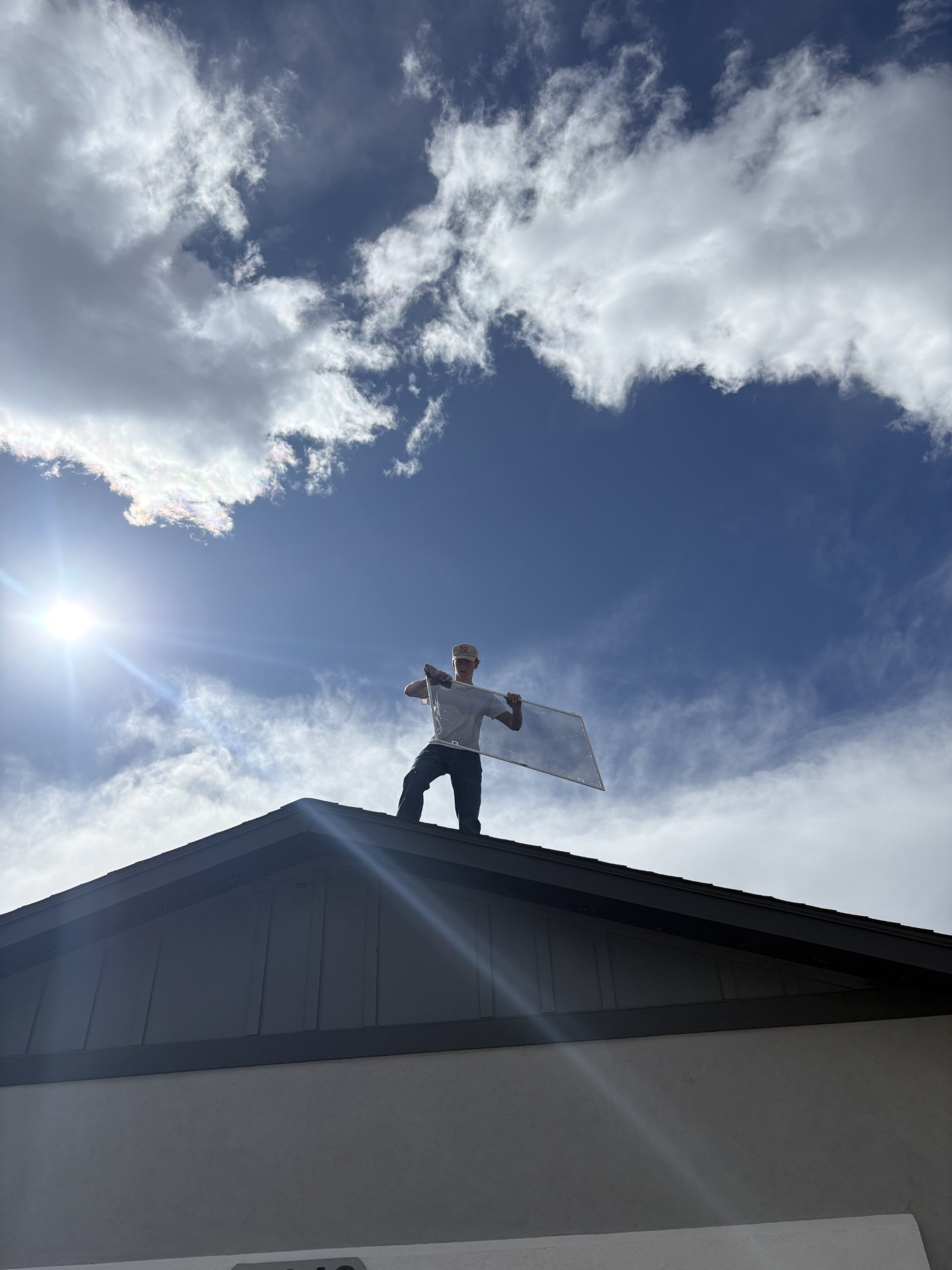 Red Wagon Windows team member holding a clean window screen on a rooftop